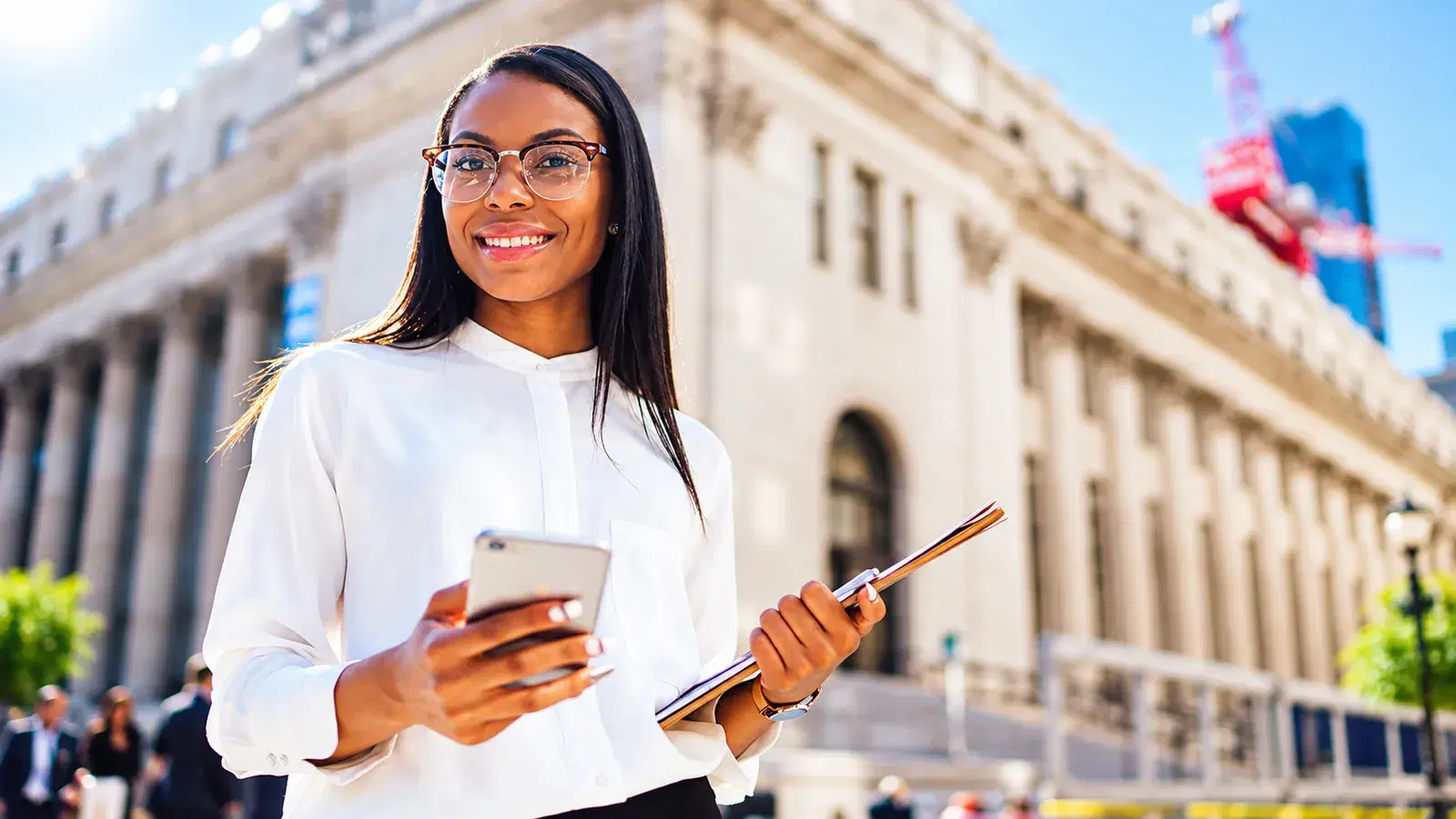 Woman in glasses holding her phone, paying with her TREDES card