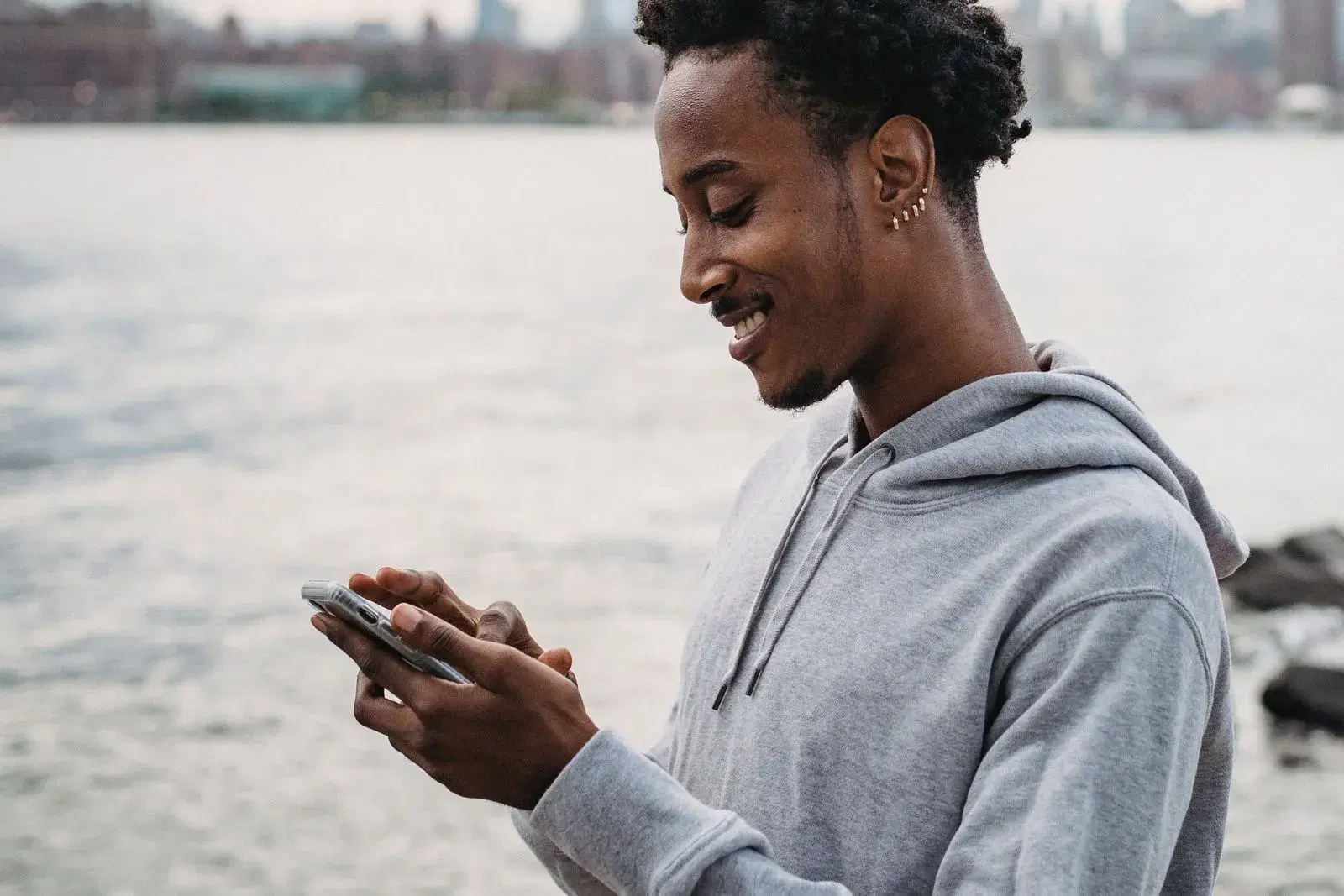 Cheerful man smiling at his phone after an instant loan lands in his wallet